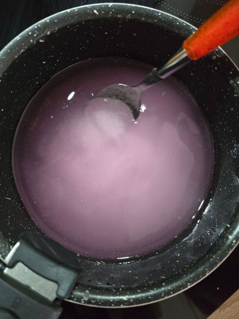 Sirop de violette rose remué à la cuillère dans une casserole