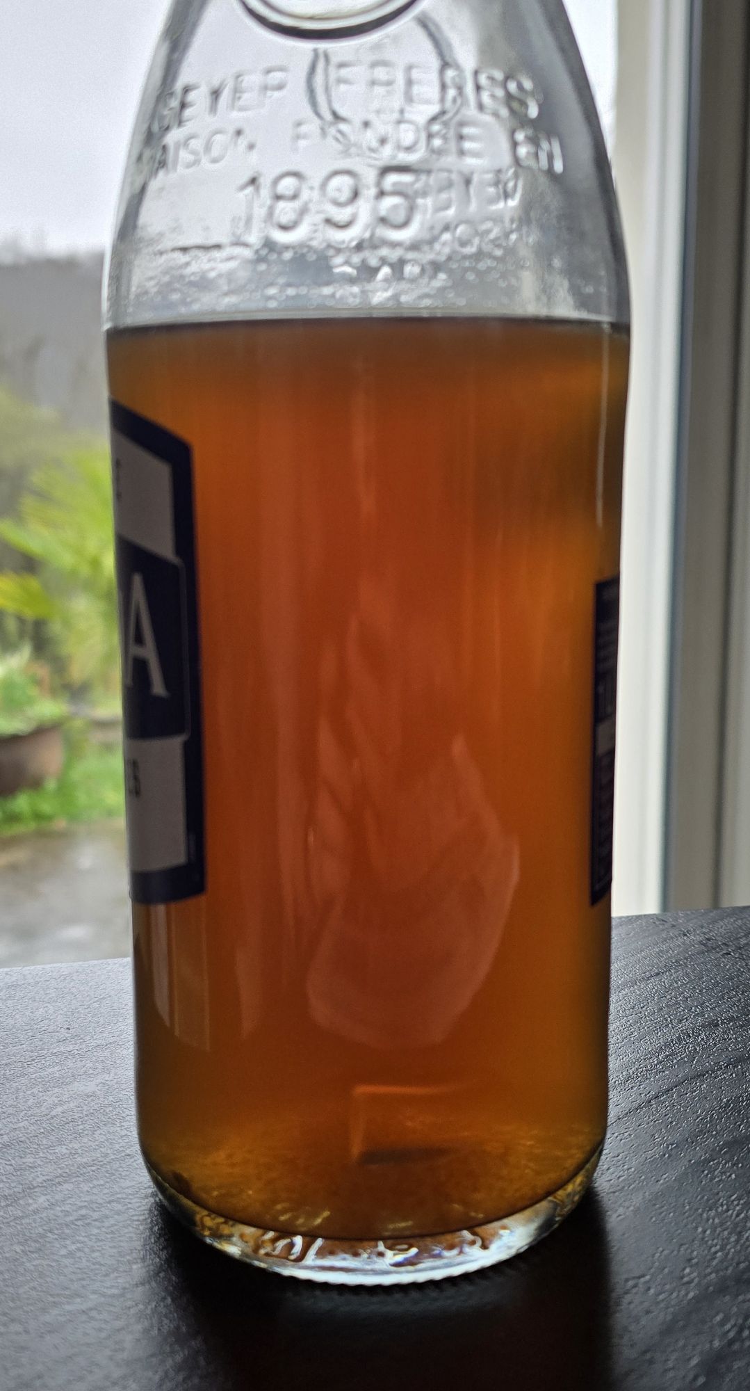 Sirop de forsythia au miel, de couleur ambrée, dans sa bouteille