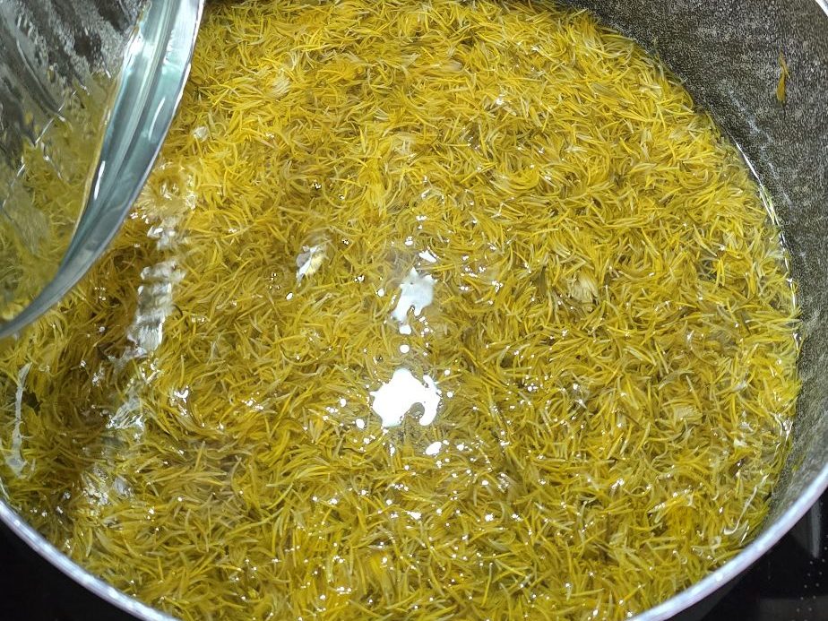 Infusion jaune de fleurons de pissenlit dans une casserole